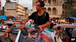 Demonstran Irak memukul poster Panglima Garda Revolusi Iran Jenderal Qassim Soleimani dengan sepatu mereka, dalam aksi protes di Baghdad (3/11). 