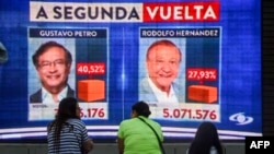 Warga menyaksikan hasil pemilihan presiden Kolombia yang terpampang di sebuah layar elektronik di Medellin, Kolombia, Minggu, 29 Mei 2022. Hasil awal menunjukkan mantan wali kota Bogota Gustavo Petro, 62 tahun, memimpin dengan 40,3% suara. (Foto: Joaquin Sarmiento/AFP)
