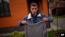 ARCHIVO - Yura Nechyporenko, de 14 años, sostiene la sudadera con capucha que tenía puesta el día que un soldado ruso intentó ejecutarlo en Bucha, en las afueras de Kiev, Ucrania, el 19 de abril de 2022.