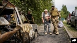 Volonter pomaže starijem čovjeku da se evakuiše iz zgrade oštećene u ruskom napadu na Slovjansk. (Foto:AP/Francisco Seco)