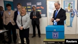 Israel's Prime Minister Benjamin Netanyahu (R) casts his ballot for the parliamentary election as his wife Sara (3rdL) stands nearby at a polling station in Jerusalem, January 22, 2013.