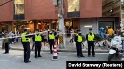 Des policiers se tiennent à côté d'un cordon de sécurité mis en place près du site où s'est déroulée une manifestation à Shanghai, en Chine, le 27 novembre 2022.