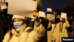 北京女子手舉白紙遊行，抗議中國嚴厲的防疫政策，悼念烏魯木齊火災死難者。（2022年11月27日）