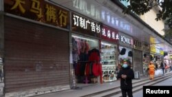 Seorang warga tampak berjalan melewati barisan toko-toko, sebagian di antaranya masih tutup, di Wuhan, China, pada 10 Desember 2022, setelah pemerintah China melonggarkan pembatasan terkait COVID-19. (Foto: Reuters/Martin Pollard)