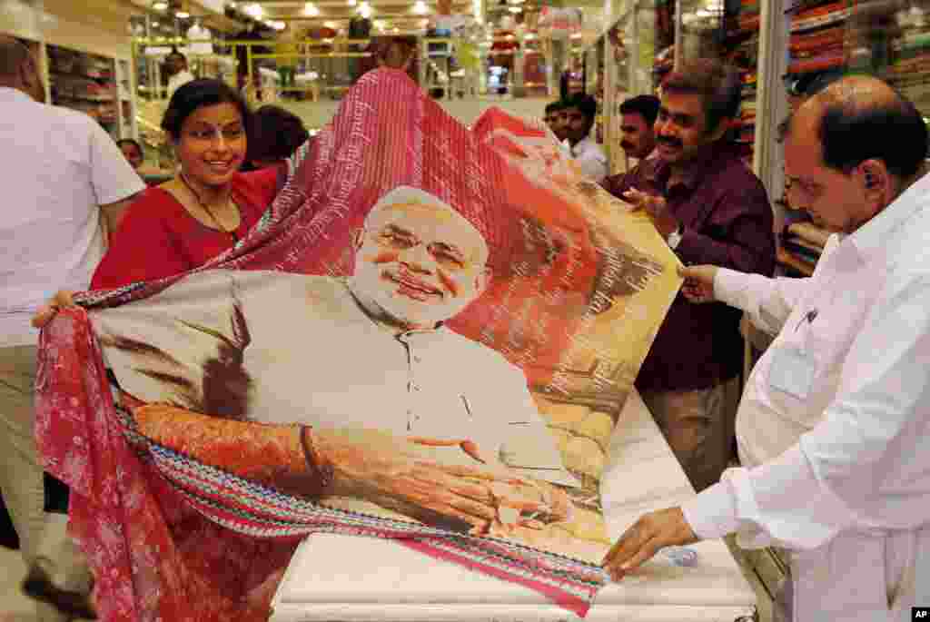 A woman holds a sari printed with a portrait of Bharatiya Janata Party's prime ministerial candidate Narendra Modi at a garments shop in Mumbai, May 14, 2014.