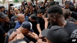 Players and officials of the soccer club Arema FC pray outside the Kanjuruhan Stadium where many fans lost their lives in a stampede Saturday night in Malang, Indonesia, Oct. 3, 2022. 