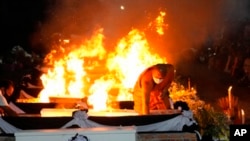 A monk lights funeral pyres to cremate those who died in the day care center attack at Wat Rat Samakee temple in Uthai Sawan, northeastern Thailand, Oct. 11, 2022.