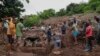 Sejumlah kerabat membantu personel SAR dari Kepolisian Afrika Seltatan (SAPS) membersihkan puing-puing dalam operasi pencaraian sepuluh orang yang hilang saat banjir di wilayah KwaNdengezi, di luar Kota Durban, Afrika selatan, 15 April 2022. (Foto: Phill Magakoe / AFP)