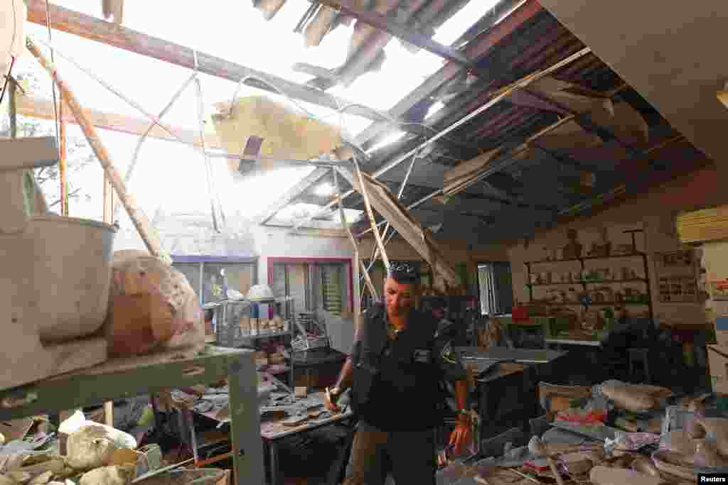 An Israeli border police officer surveys the damaged caused to a structure after it was hit by a rocket, near the border with the Gaza Strip, July 9, 2014.