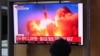 People watch a television news broadcast showing file footage of a North Korean missile test, at a railway station in Seoul on September 28, 2021, after North Korea fired an "unidentified projectile" into the sea off its east coast, according to the South