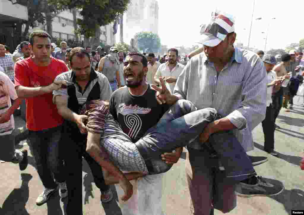 Supporters of former Egyptian President Mohamed Morsi carry an injured man during clashes outside the Republican Guard building in Cairo, July 5, 2013. 