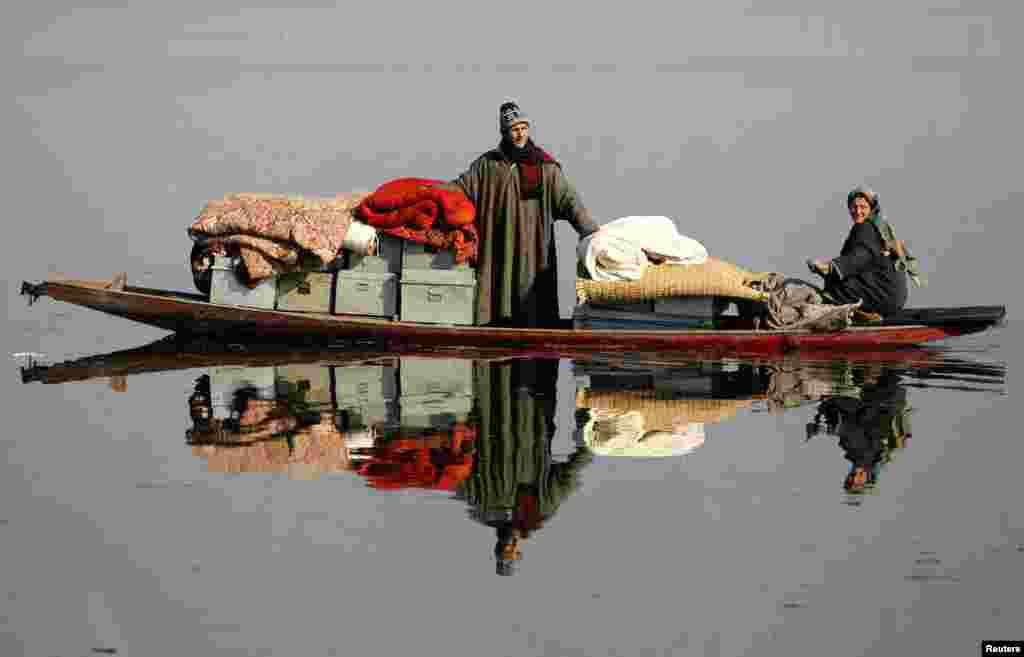 Dua warga Kashmir mengamankan barang-barang mereka setelah terjadi kebakaran di desa Dhobi Ghat, pinggiran kota Srinagar, Kashmir-India.
