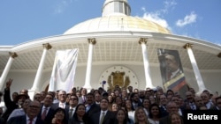 FILE - Deputies of Venezuelan coalition of opposition parties (MUD) pose for a picture in front of a giant picture of Venezuela's late President Hugo Chavez after a session of the National Assembly in Caracas, Jan. 5, 2016.