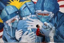 FILE - A doctor collects a swab sample from a man to be tested for the coronavirus disease outside Clinic Ajwa in Shah Alam, Malaysia.