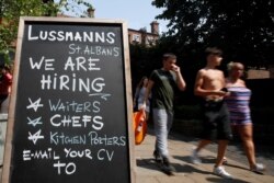 People walk past a sign, amid the spread of the coronavirus disease (COVID-19), in St Albans, Britain, July 21, 2021.