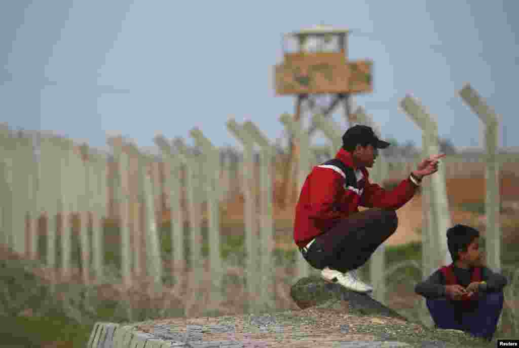 Youths sit next to a row of barbed wire near the Syrian border, Sanliurfa province, Turkey, November 30, 2012.