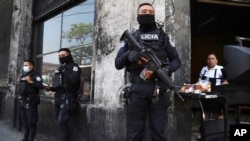 Policías con armas largas custodian las calles después de que el Congreso de El Salvador aprobara el estado de emergencia solicitado por el presidente Nayib Bukele, en medio de una ola de asesinatos relacionados con pandillas, en el centro de San Salvador, el 27 de marzo de 2022.