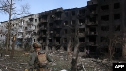 Seorang polisi Ukraina berjalan melewati bangunan tempat tinggal yang hancur, menyusul serangan artileri dan udara di desa Ocheretyne, dekat kota Avdiivka, di wilayah Donetsk, 15 April 2024.