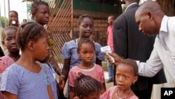 Un trabajador de la salud toma la temperatura a escolares en busca de síntomas de ébola, antes de que ingrersen a clase, en Conakry, Guinea.