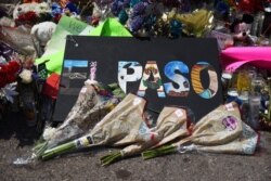 FILE - Flowers and candles are left at a memorial five days after a mass shooting at a Walmart store in El Paso, Texas, Aug. 8, 2019.