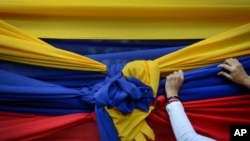 Un manifestante sostiene una tela con los colores de la bandera venezolana antes de un mitin con el líder opositor Juan Guaidó en Caracas, el 11 de enero de 2020.