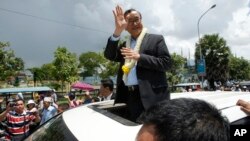 FILE - In this Aug. 16, 2015 file photo, Sam Rainsy, leader of the opposition Cambodia National Rescue Party (CNRP), waves from a car upon his arrival at Phnom Penh International Airport in Phnom Penh, Cambodia as hundreds of cheering supporters greeted him on his return from a trip abroad. The head of Cambodia's opposition party has announced his resignation from the group after the country's long-serving prime minister announced plans for a law that could lead to the party's dissolution. Rainsy announced his resignation Saturday, Feb. 11, 2017 in a letter to his Cambodia National Rescue Party.(AP Photo/Heng Sinith, File)