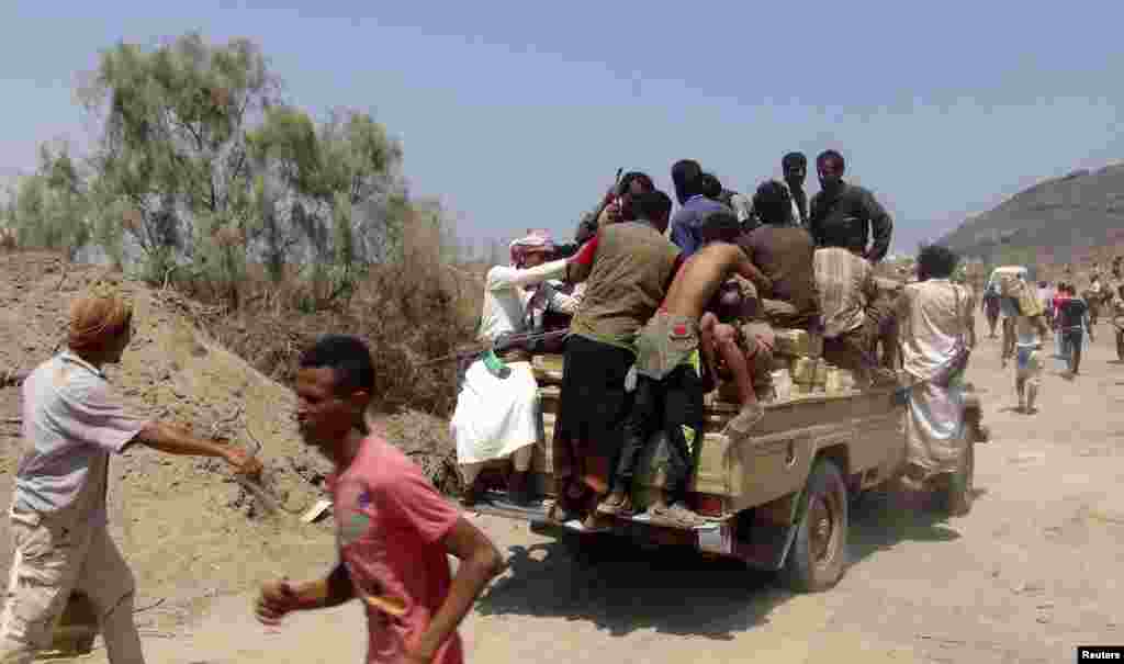 People sit on boxes of ammunition looted from an army depot in Aden, March 27, 2015.