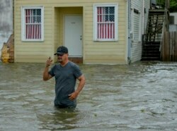 Barry Williams talks to a friend on his smartphone as he wades through storm surge from Lake Pontchartrain on Lakeshore Drive in Mandeville, La., as Hurricane Barry approached, July 13, 2019.