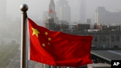 FILE - Bendera nasional China berkibar di depan gedung perkantoran di Shanghai, 14 April 2016. (AP/Andy Wong, File).