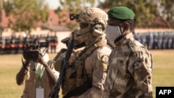 Le président malien de transition, le colonel Assimi Goïta (à droite) regarde après avoir déposé une gerbe sur le monument aux morts, lors de la cérémonie célébrant la fête nationale de l'armée, à Kati, le 20 janvier 2022.