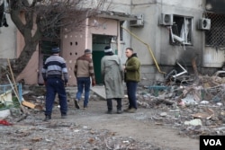 Men enter a mostly destroyed building to search for any of their belongings still intact, in Borodyanka, Ukraine, April 6, 2022. (Heather Murdock/VOA)