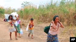 Displaced people from Myanmar carry donated lunch boxes to their tents along the Thai side of the Moei River in Mae Sot, Thailand, on Feb. 5, 2022.