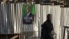 A woman walks past a campaign poster of a presidential candidate Alassane Ouattara of the ruling RHDP coalition, in Attecoube district, Abidjan, Ivory Coast, Oct. 23, 2020. 