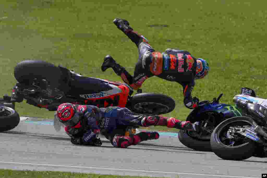 South African rider Brad Binder of Red Bull KTM Factory Racing, top, leaps in the air after crashing with French rider Fabio Quartararo of Monster Energy Yamaha during the start of the MotoGP race in Sepang, outskirts of Kuala Lumpur, Malaysia.
