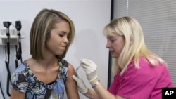 Lauren Fant, left, 18, winces as she has her third and final application of the HPV vaccine administered by nurse Stephanie Pearson at a doctor's office Tuesday, Dec. 18 2007, in Marietta, Ga. This groundbreaking vaccine that prevents cervical cancer in g
