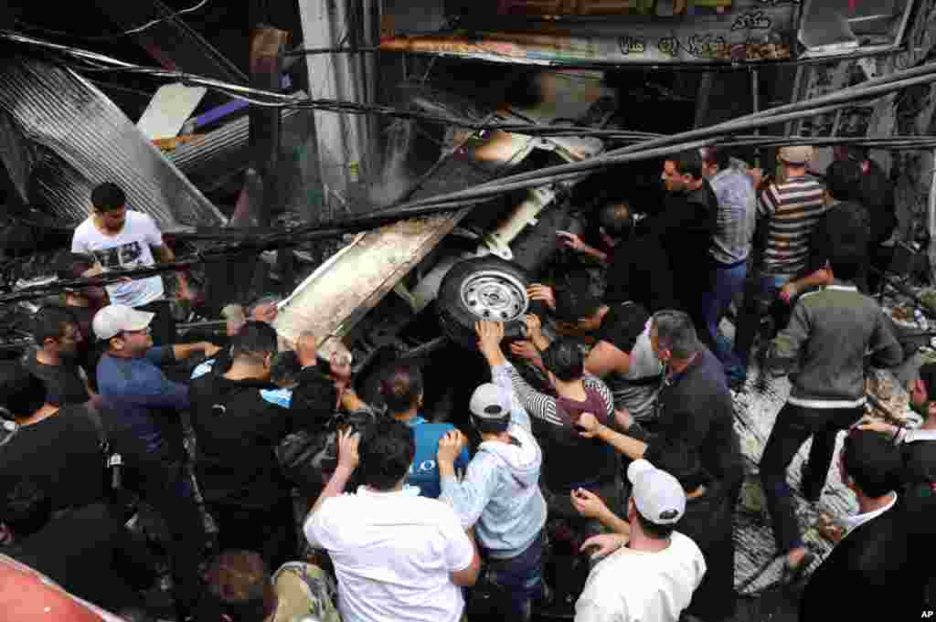 This photo released by the Syrian official news agency SANA shows Syrians pushing a car at the scene after a blast in Damascus, Syria, November 5, 2012.