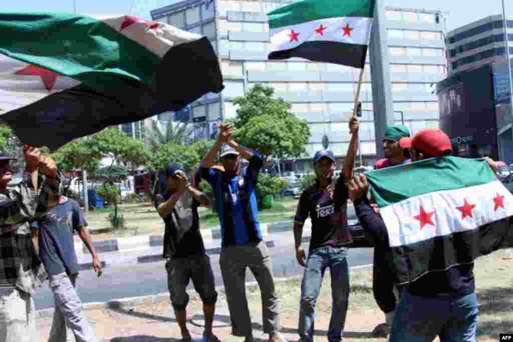 Men celebrate in the Lebanese town of Tripoli on July 18, 2012, after an attack in Damascus killed the Syria's defense minister, General Daoud Rajha.