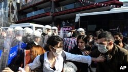 Turkish police officers, in riot gear, and wearing face masks for protections against the spread of the coronavirus, scuffle with protesters during a demonstration in Istanbul, June 2, 2020, against the recent killing of George Floyd in Minneapolis.