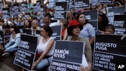 FILE - Anti-government demonstrators hold the names of people killed during months of deadly protests against Venezuelan President Nicolas Maduro, at a park in Caracas, Venezuela, Aug. 30, 2017. 