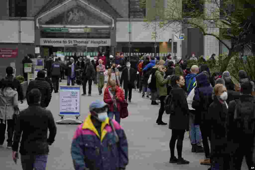 People queue in a line for coronavirus booster jabs at St. Thomas' Hospital, in London.
