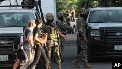 Two women walk next to members of Mexican Navy in Boca del Rio, Veracruz State. Another 32 bodies have been found in three homes in Mexico's eastern state of Veracruz, where dozens of corpses were dumped on a road in broad daylight last month, the navy sa