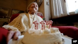 FILE - Emma Morano holds a cake with candles marking 117 years on the day of her birthday, Nov. 29, 2016, in Verbania, Italy. A new study says that while the number of centenarians will grow, humans are hitting the upper limit of life expectancy.