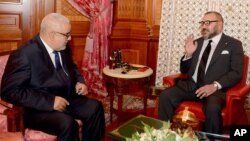 FILE - In this photo provided by the Royal Palace, Moroccan King Mohammed VI, right, chats with Moroccan head of the country's government Abdelilah Benkirane in Casablanca, Morocco, Oct. 10, 2016. 