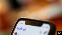 FILE - A smartphone displays a Facebook page in an illustration photo taken Aug. 11, 2019. 