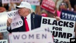 Republican presidential candidate Donald Trump kisses a "Women for Trump" sign during a campaign rally, Wednesday, Oct. 12, 2016, in Lakeland, Florida. 