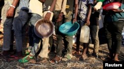 FILE - Ethiopian refugees who fled the country's restive Tigray region queue to receive food aid at the Um-Rakoba camp in Al-Qadarif state, in Sudan, Dec. 11, 2020.
