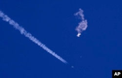 Sisa-sisa balon besar melayang di atas Samudra Atlantik, tepat di lepas pantai Carolina Selatan, dengan jet tempur dan asapnya terlihat di bawahnya, 4 Februari 2023. (Foto: via AP)