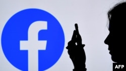 En esta ilustración de fotografía de archivo, una persona mira un teléfono inteligente con el logotipo de la aplicación de Facebook en el fondo, el 17 de agosto de 2021, en Arlington, Virginia.