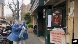 Workers in protective gear call out to residents to take part in the first round of mass COVID-19 testing in the Jingan district of western Shanghai, China, April 1, 2022.