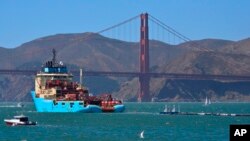 FILE - A ship tows The Ocean Cleanup's first buoyant trash-collecting device toward the Golden Gate Bridge in San Francisco en route to the Pacific Ocean, Sept. 8, 2018.